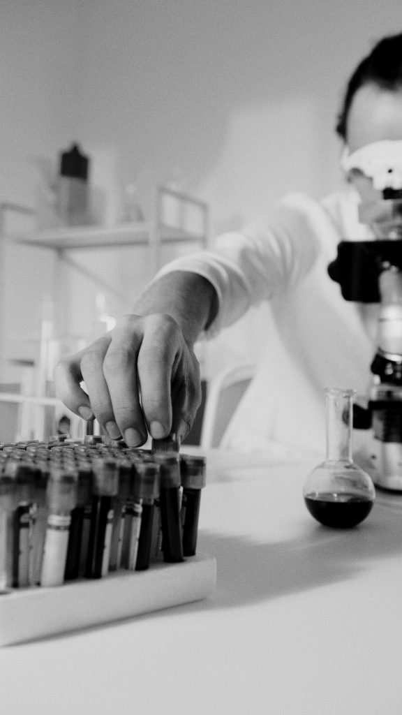 Focused scientist working with microscope and test samples in lab.