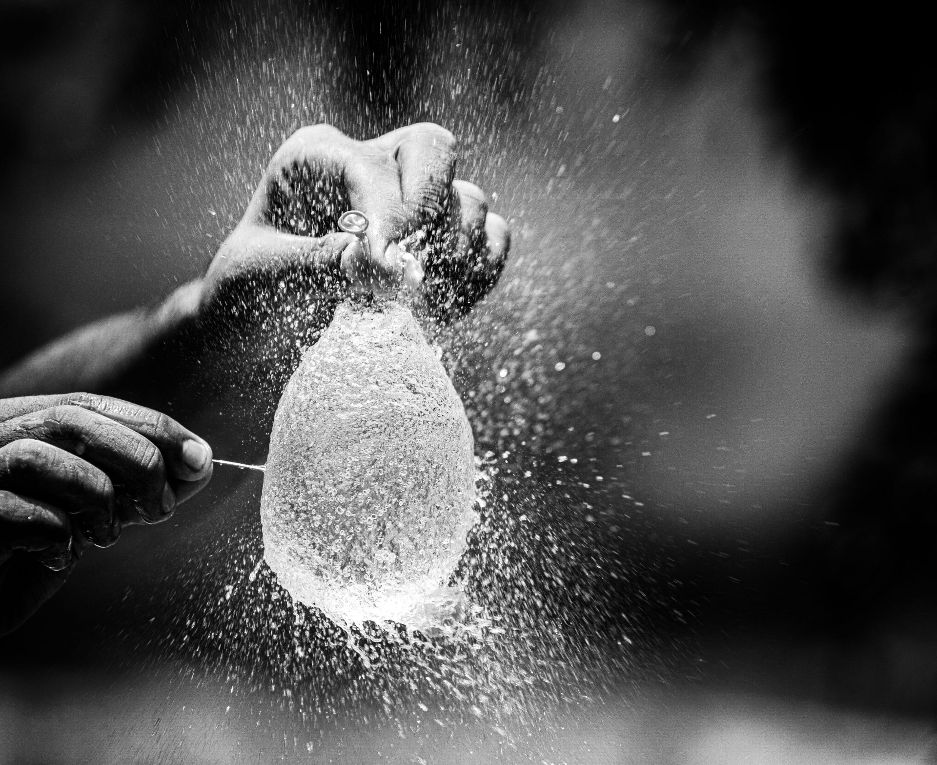 Captivating moment of a water balloon explosion captured in monochrome, showcasing motion and texture.