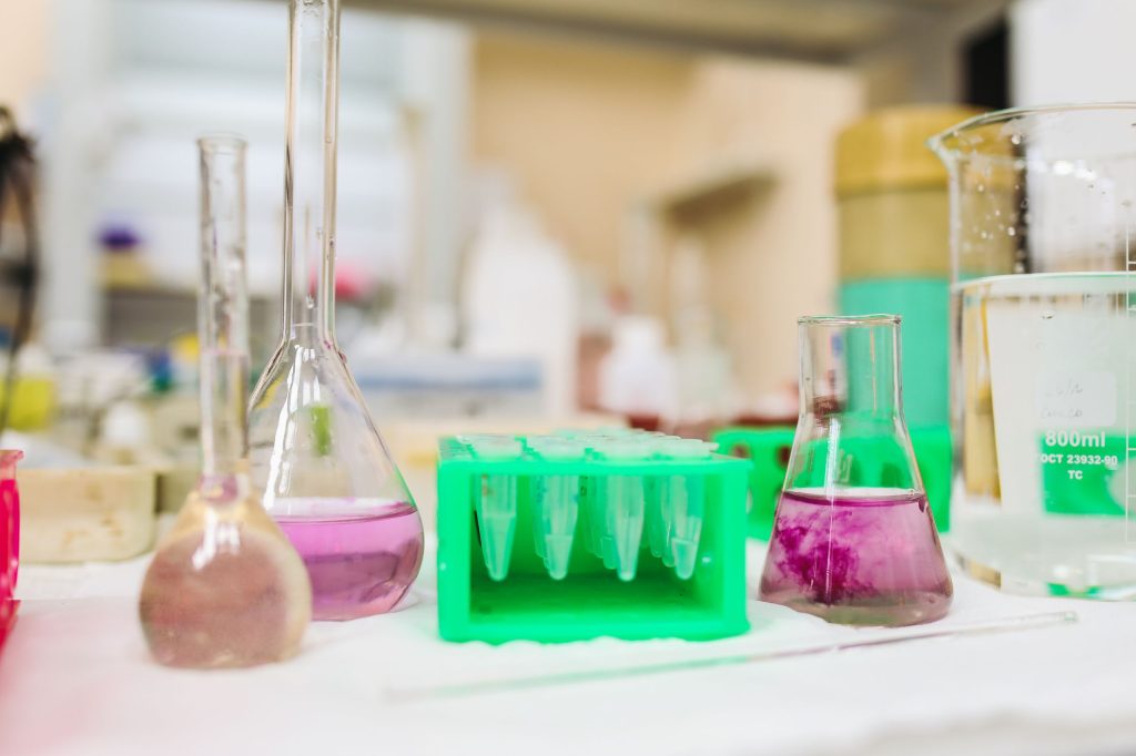A variety of laboratory glassware with colorful liquids in a science lab setting.